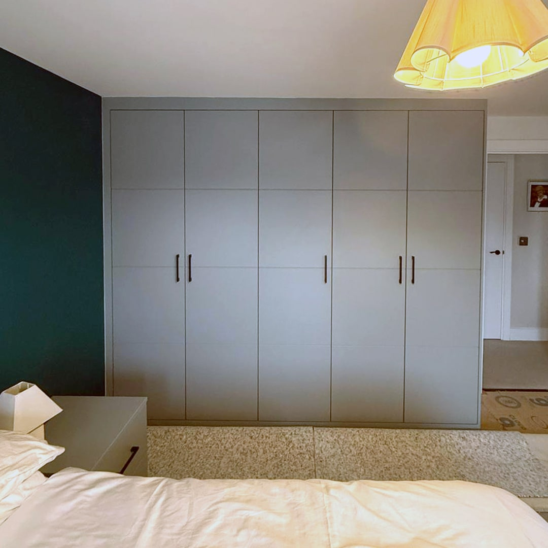Light grey flat-panel fitted wardrobes in a contemporary bedroom
